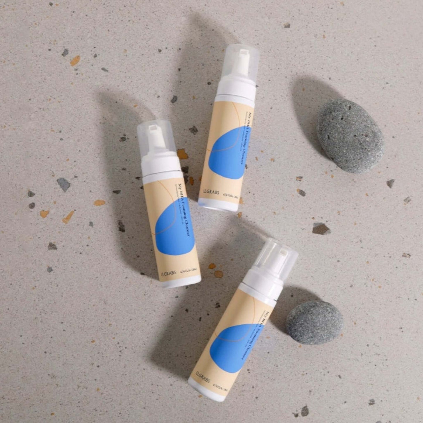BHA foaming cleanser for acne-prone skin bottles on a stone surface.