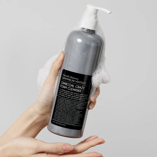 Charcoal foam cleanser 500ml by GRAYMELIN in a hand, showcasing rich foam and sleek charcoal packaging.